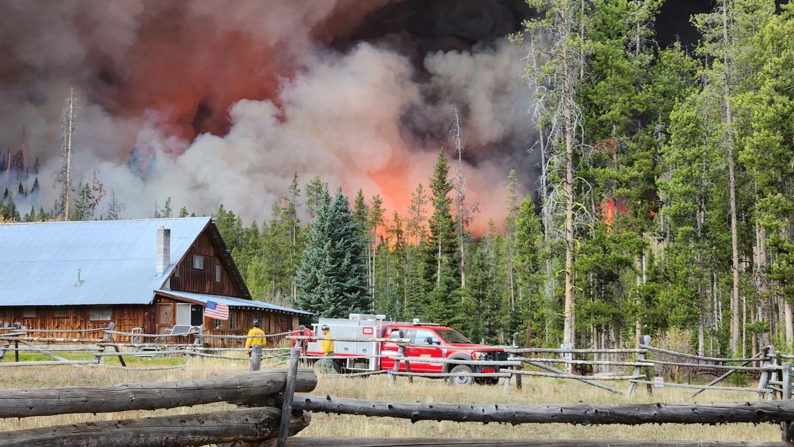 Photos shows a structure with the Logan Fire behind it.