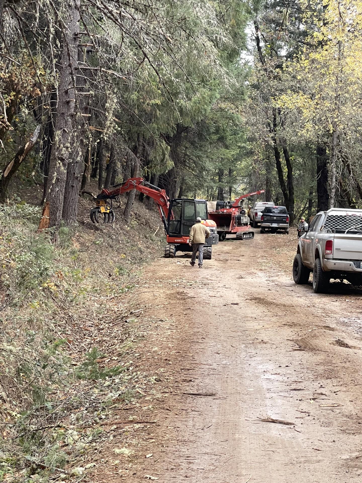 An excavator and chipper working together to clean up woody debris.