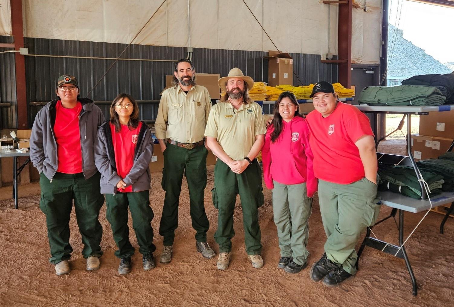 Group stands inside a fire camp building posing for a photograph.