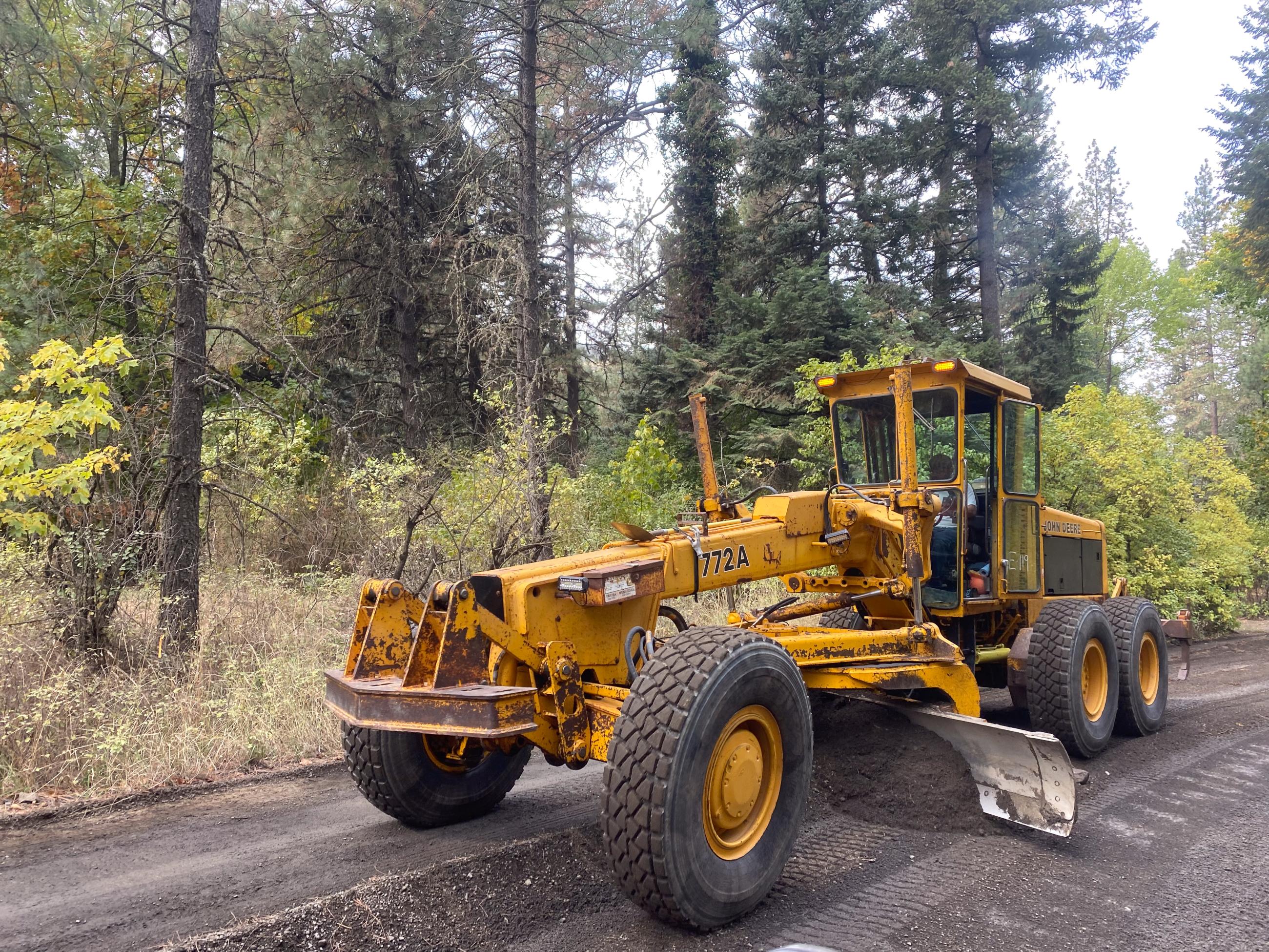 Road grading machine smooths out gravel road