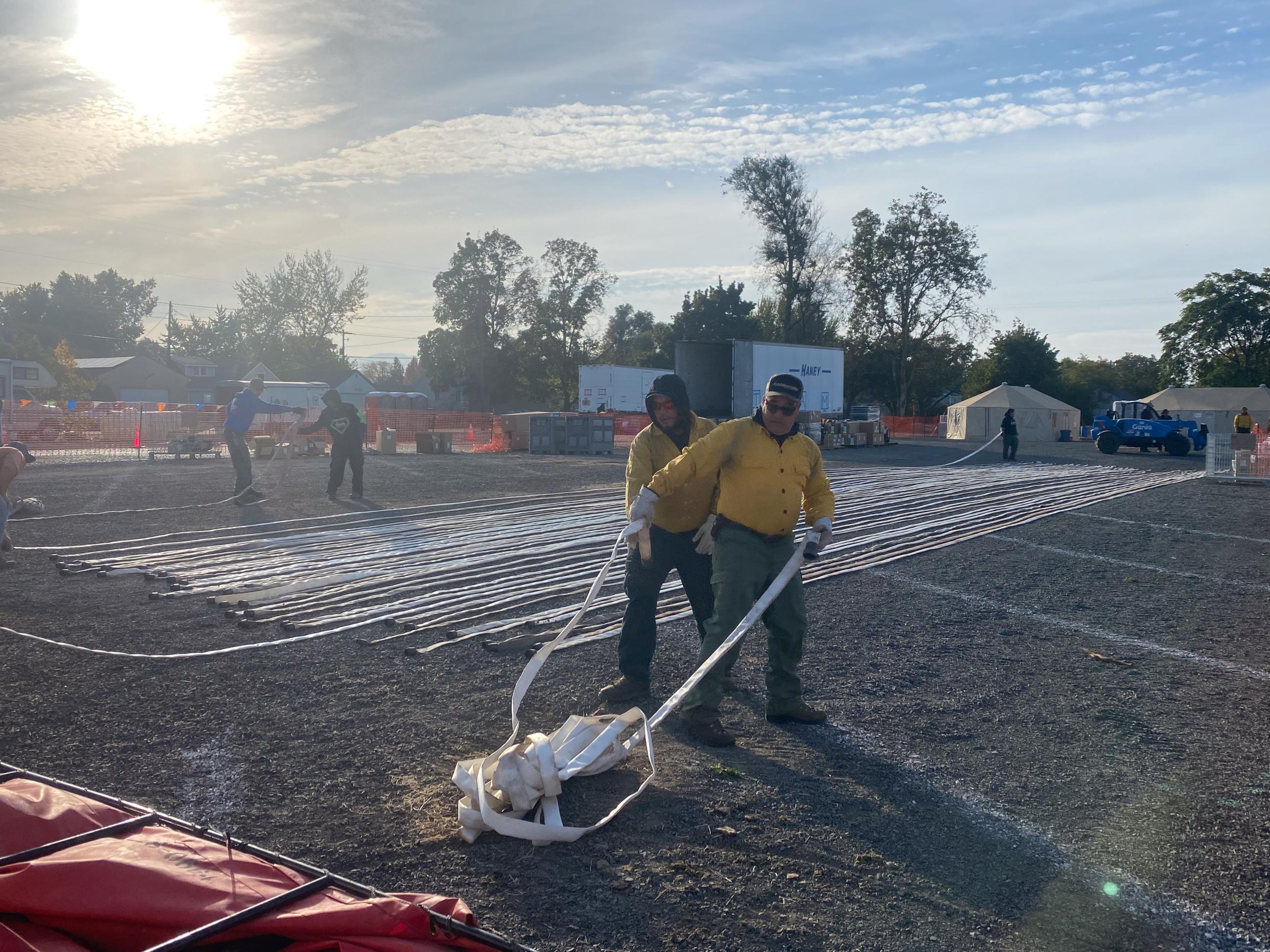 Two crew members straighten out length of white hose