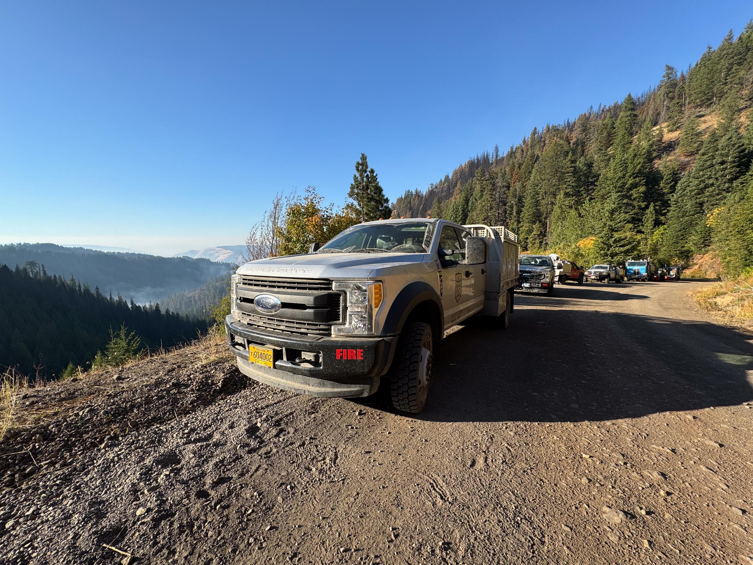 line of trucks parked on edge of gravel ridge road