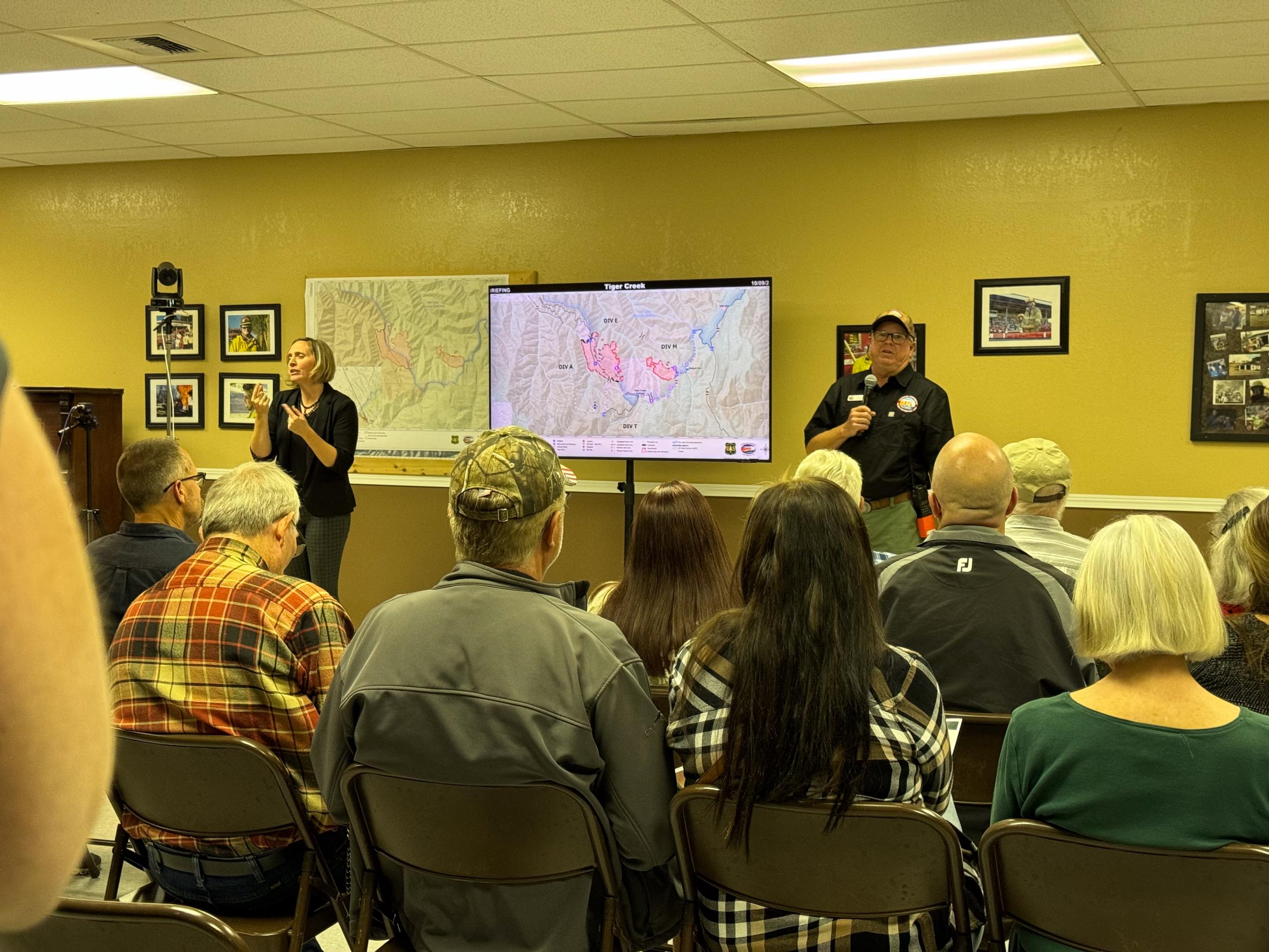 Large group of people facing a TV with a map 