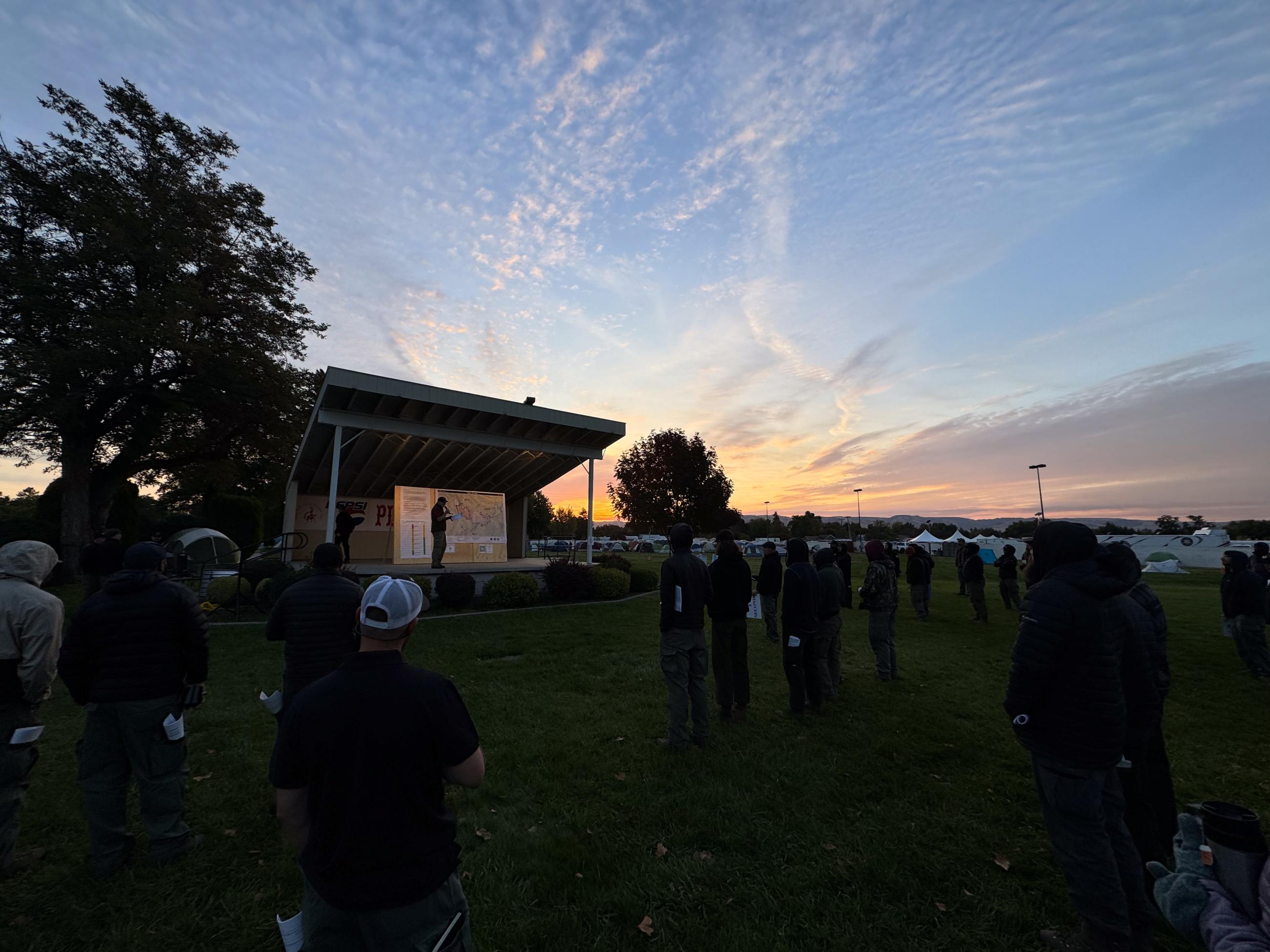 sunrise over morning briefing with many figures in the dark