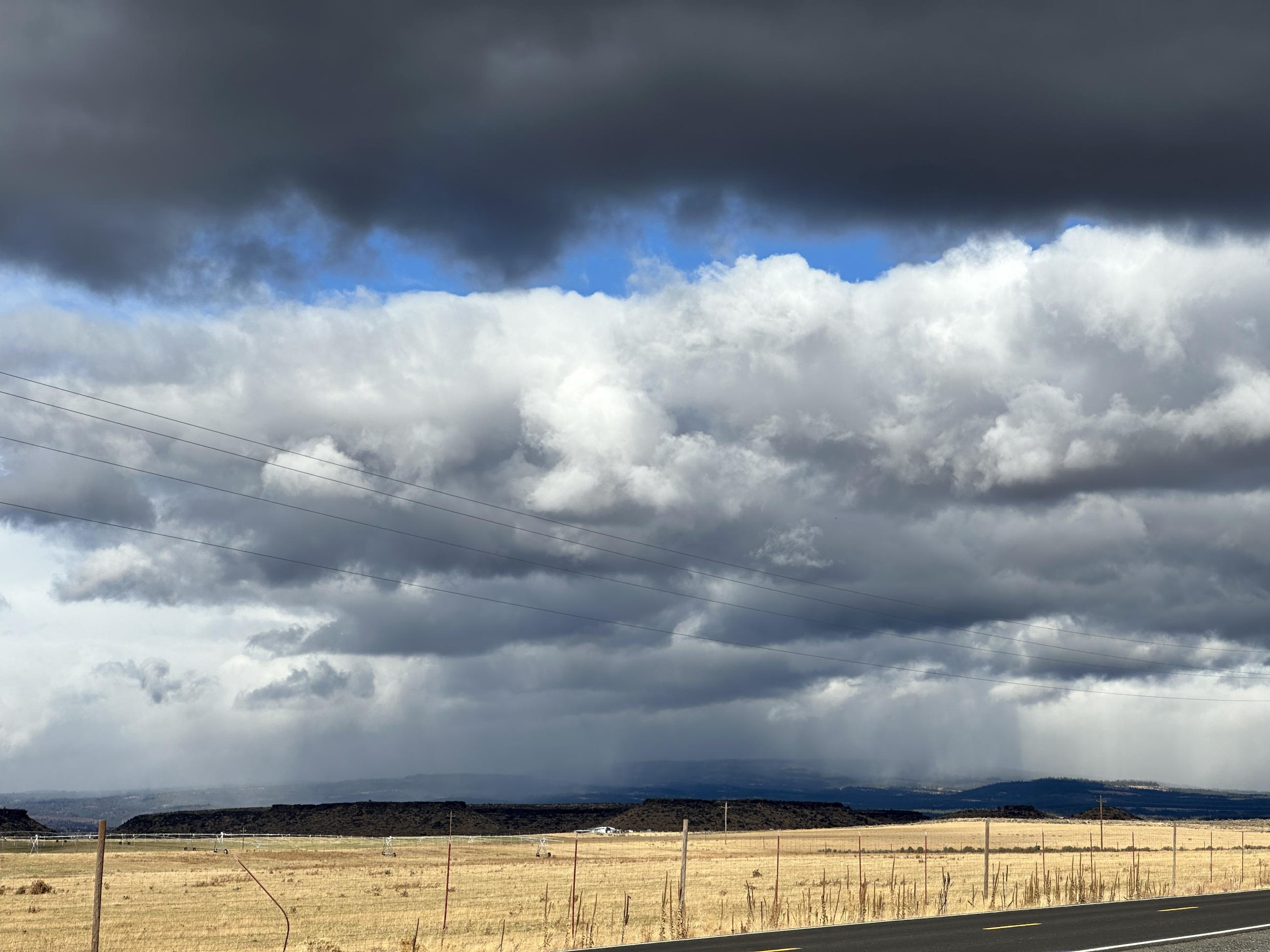 A photo of clouds and snow falling in the distance on the Rail Ridge Fire