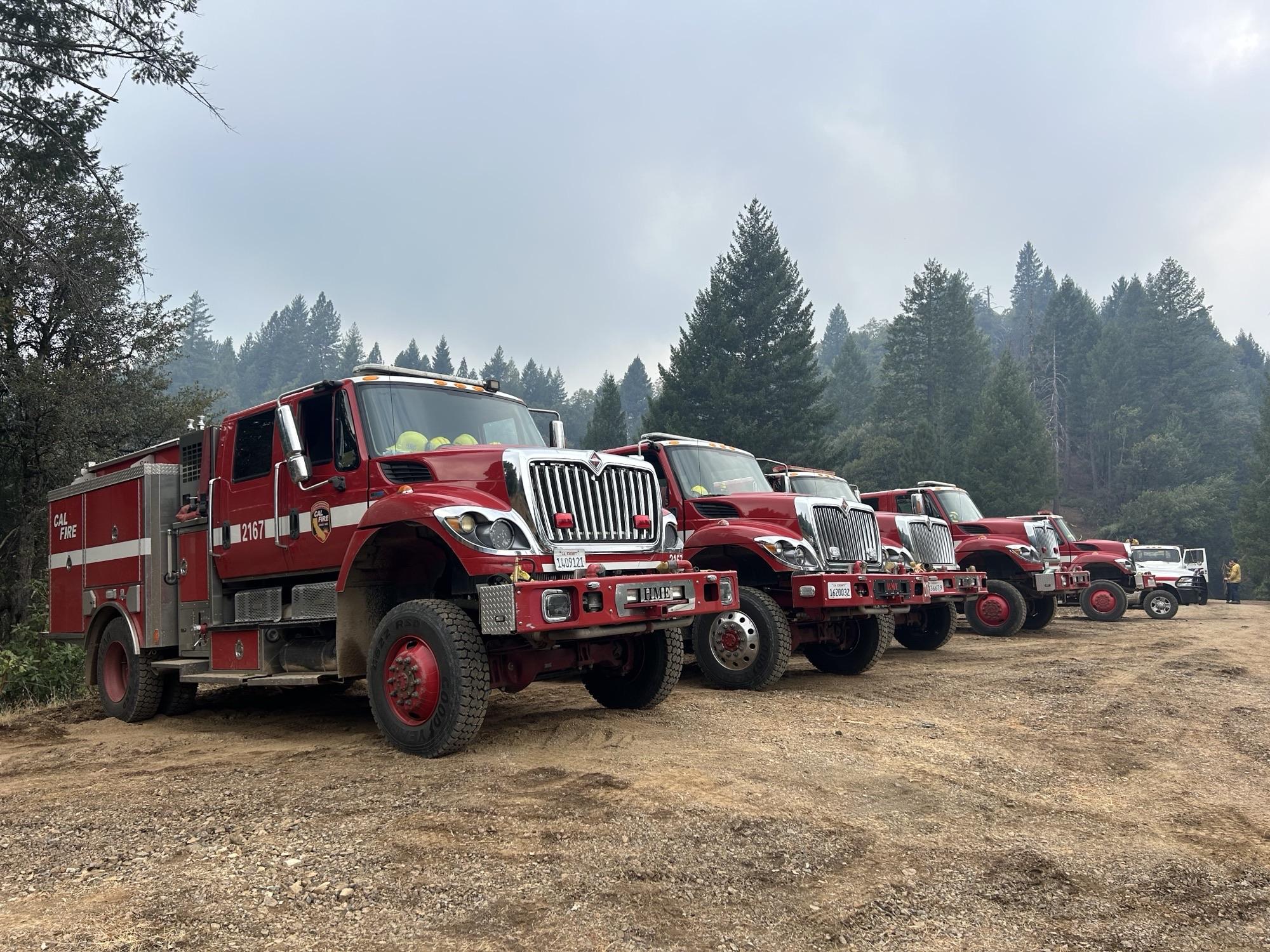 Orderly rows of CAL FIRE engines stage in a parking lot.