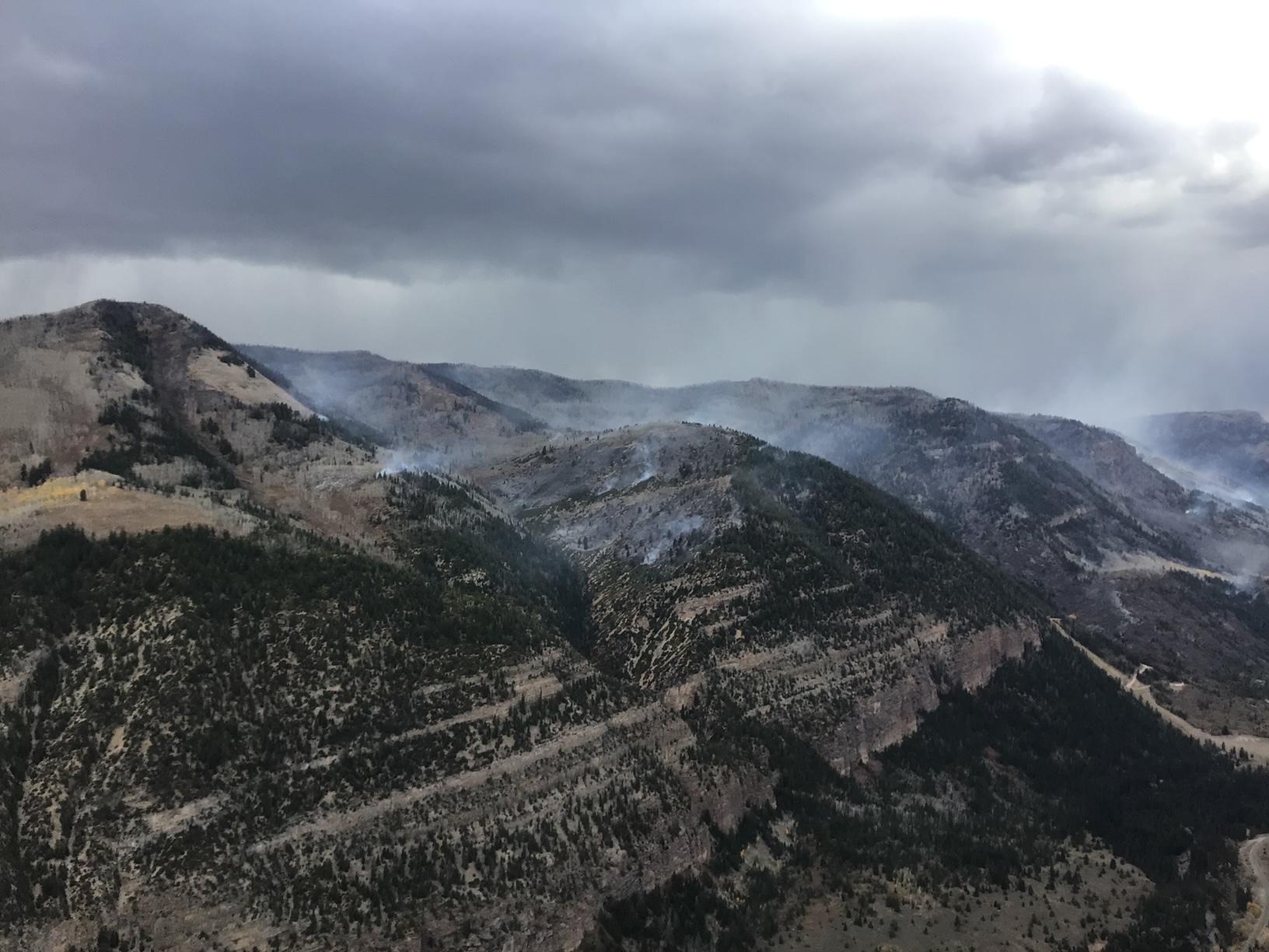 Large mountain side with smoke hovering.