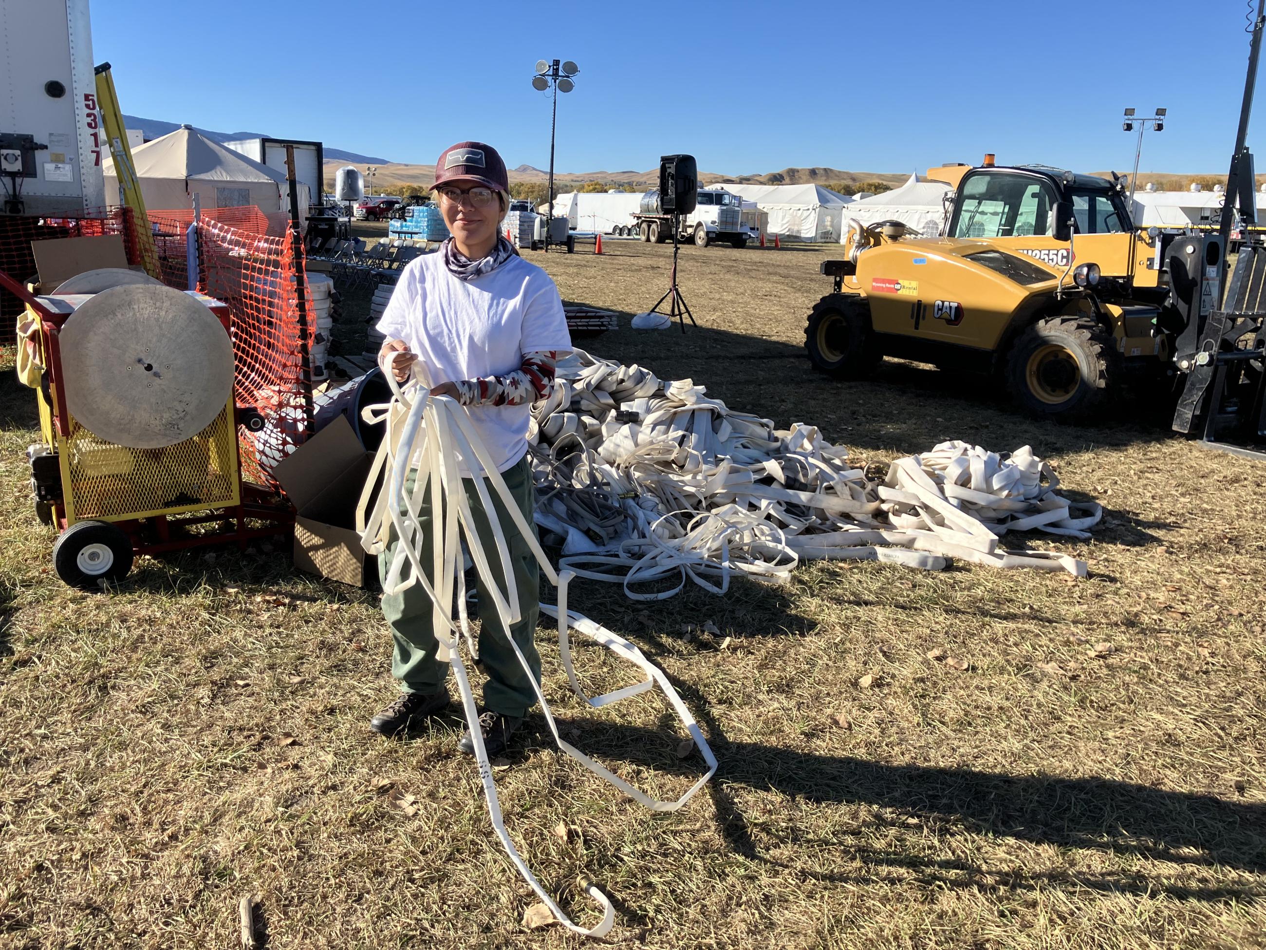 a young woman untangles used fire hose for packing