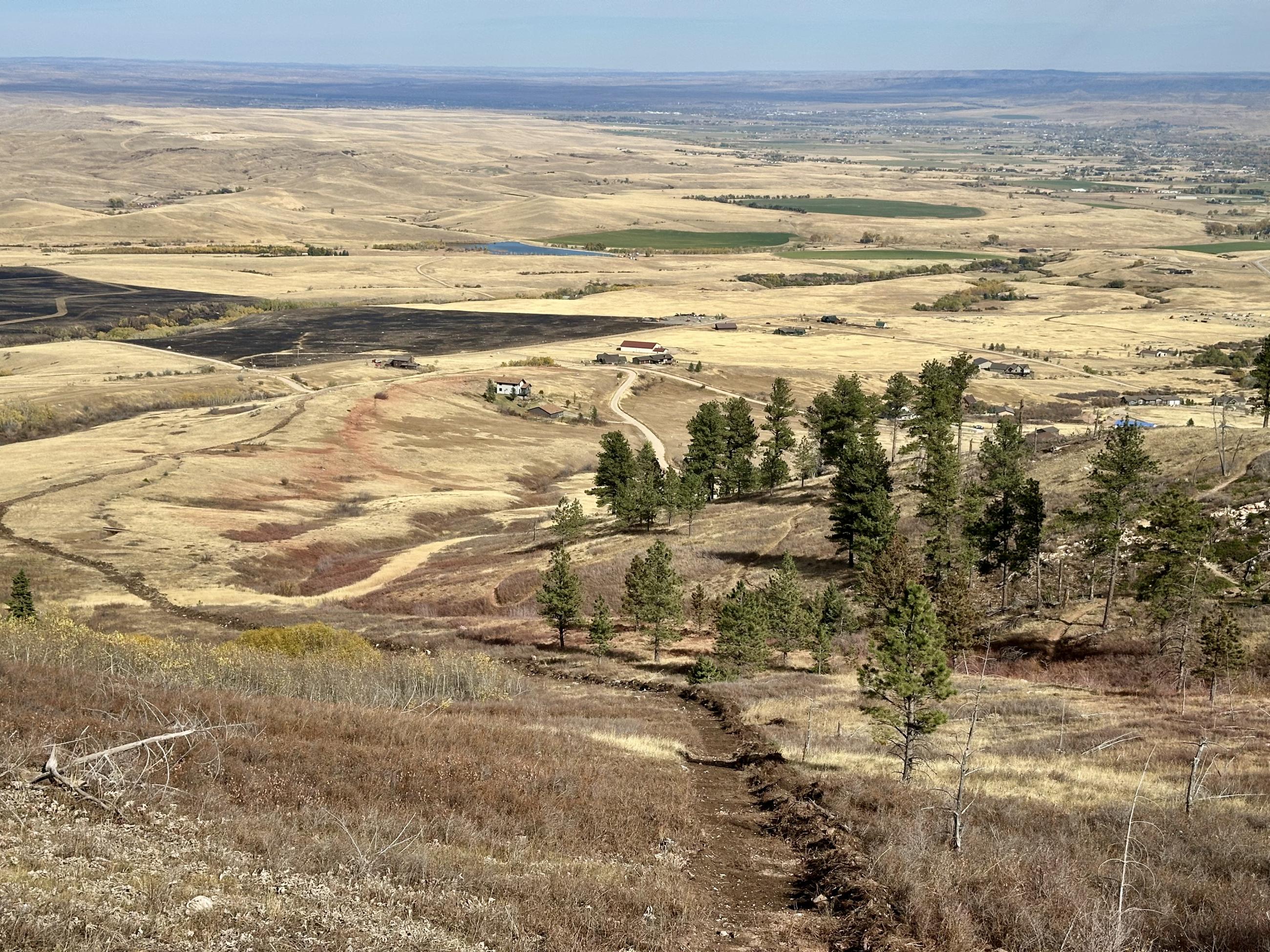 a hand dug fieline heads down a steep slope towards a house in the distance