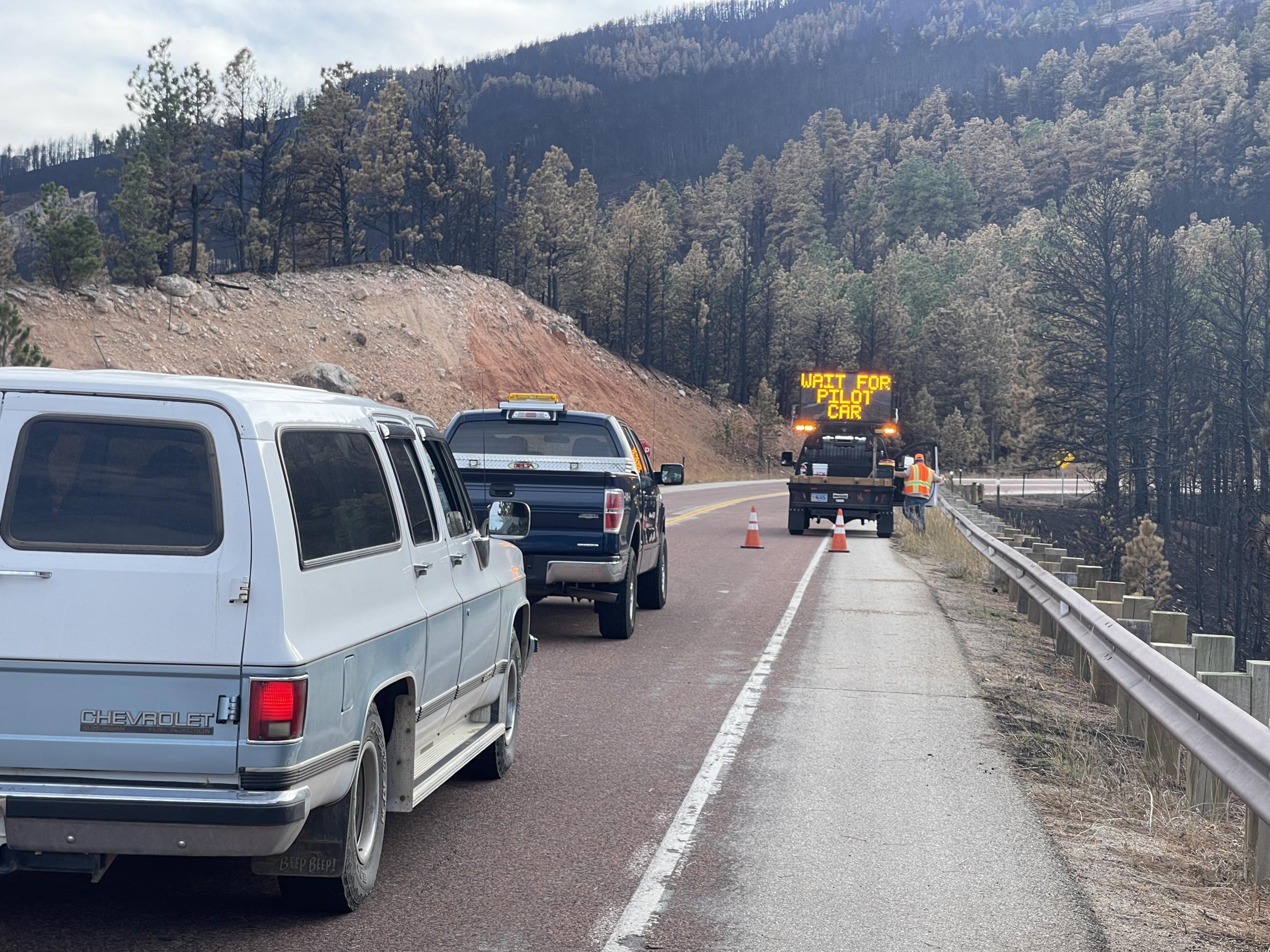 WYDOT personnel block traffic with a sign while repairing guardrails