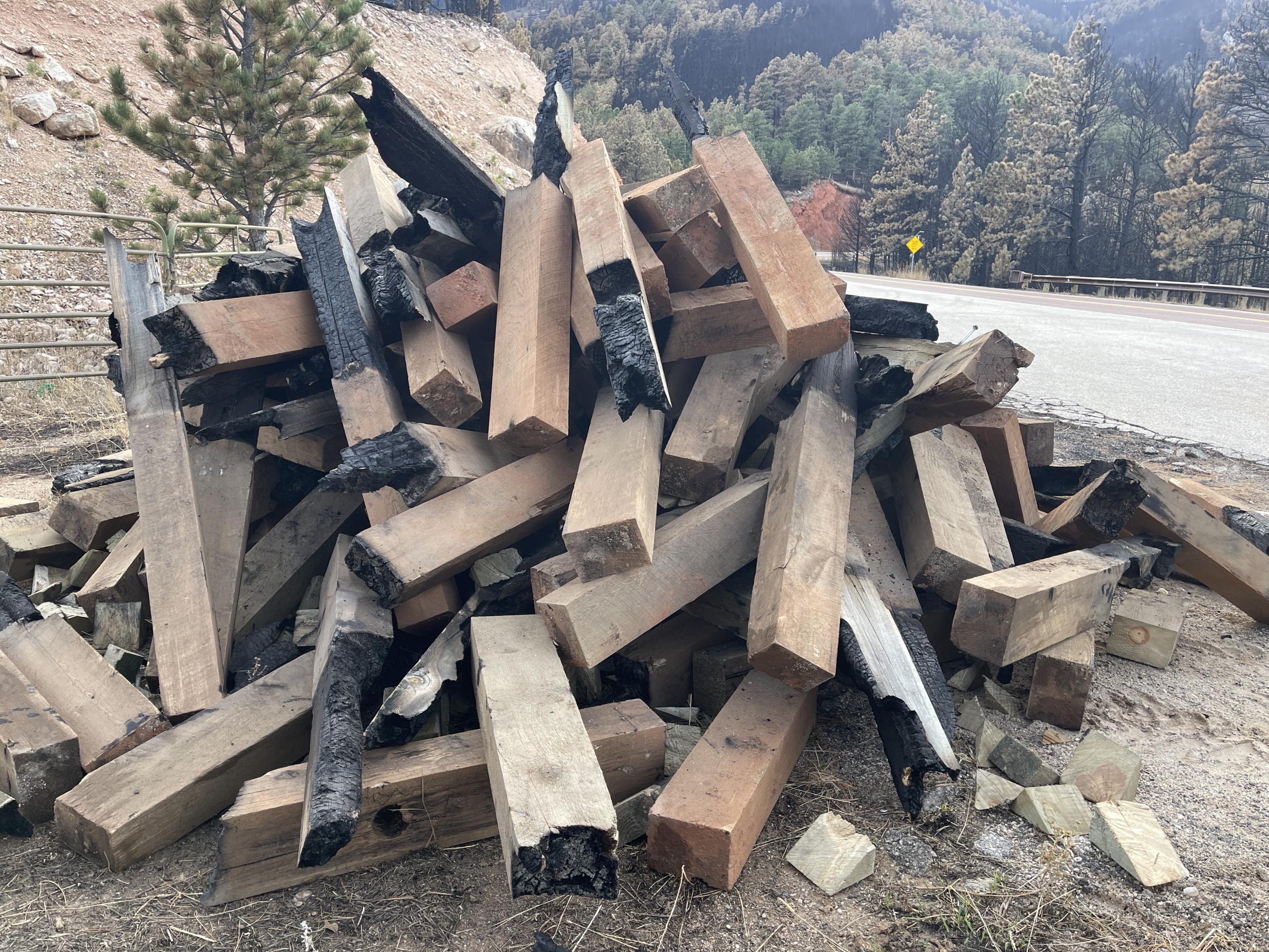 a large pile of partially burned guardrail posts along Hwy 14