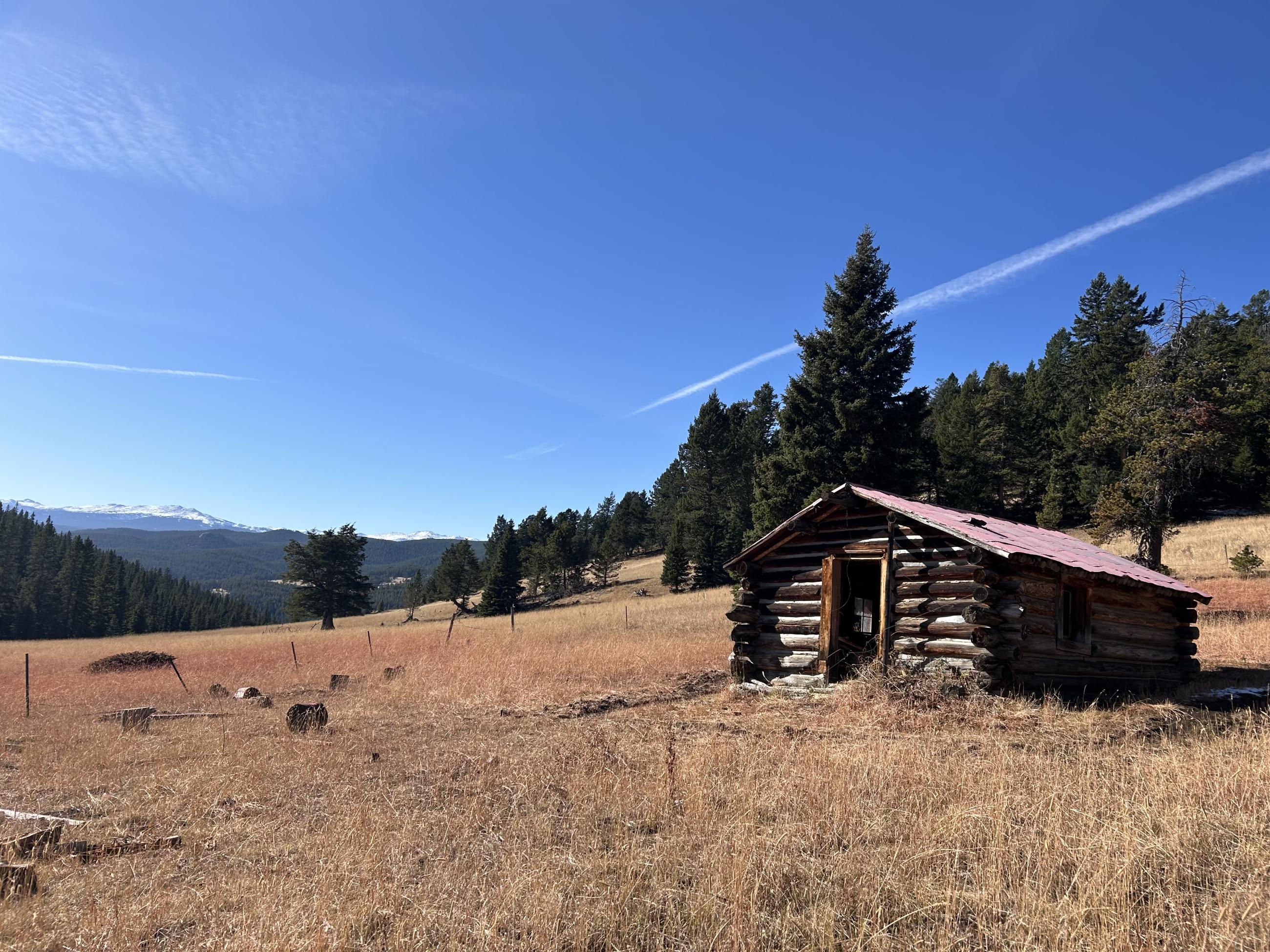 Remote cabin with remnants of fire retardant in dry grass in background, oct 25