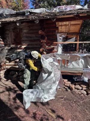  A firefighter remove reflective protective wrap from a remote cabin oct 25