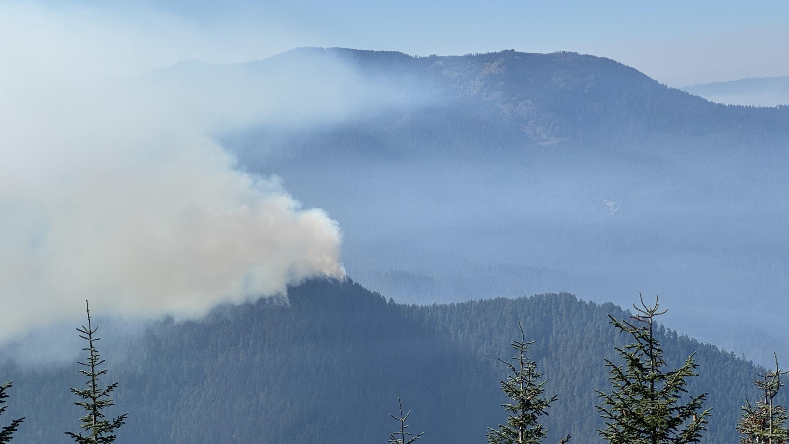 Distance view of a mountain ridge with wildfire smoke rising from it