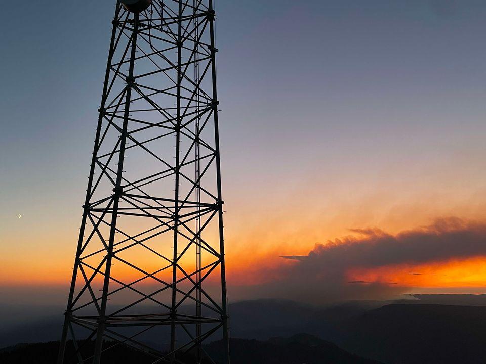 Communcation tower in the foreground with the sunset and smoke column from the Rail Ridge Fire in the background