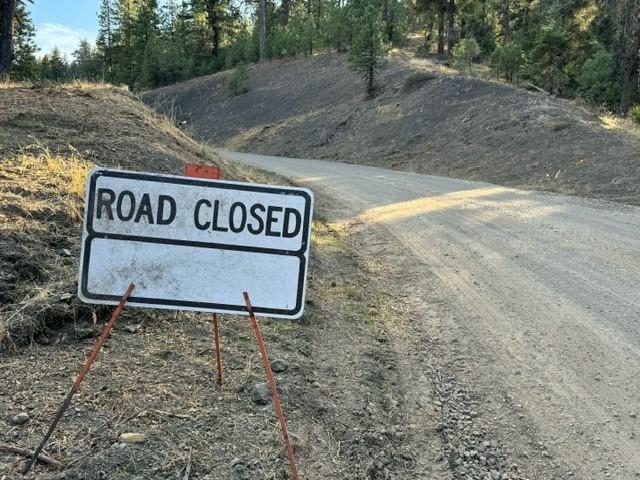 A "Road Closed" sign is shown on a gravel Forest Service road