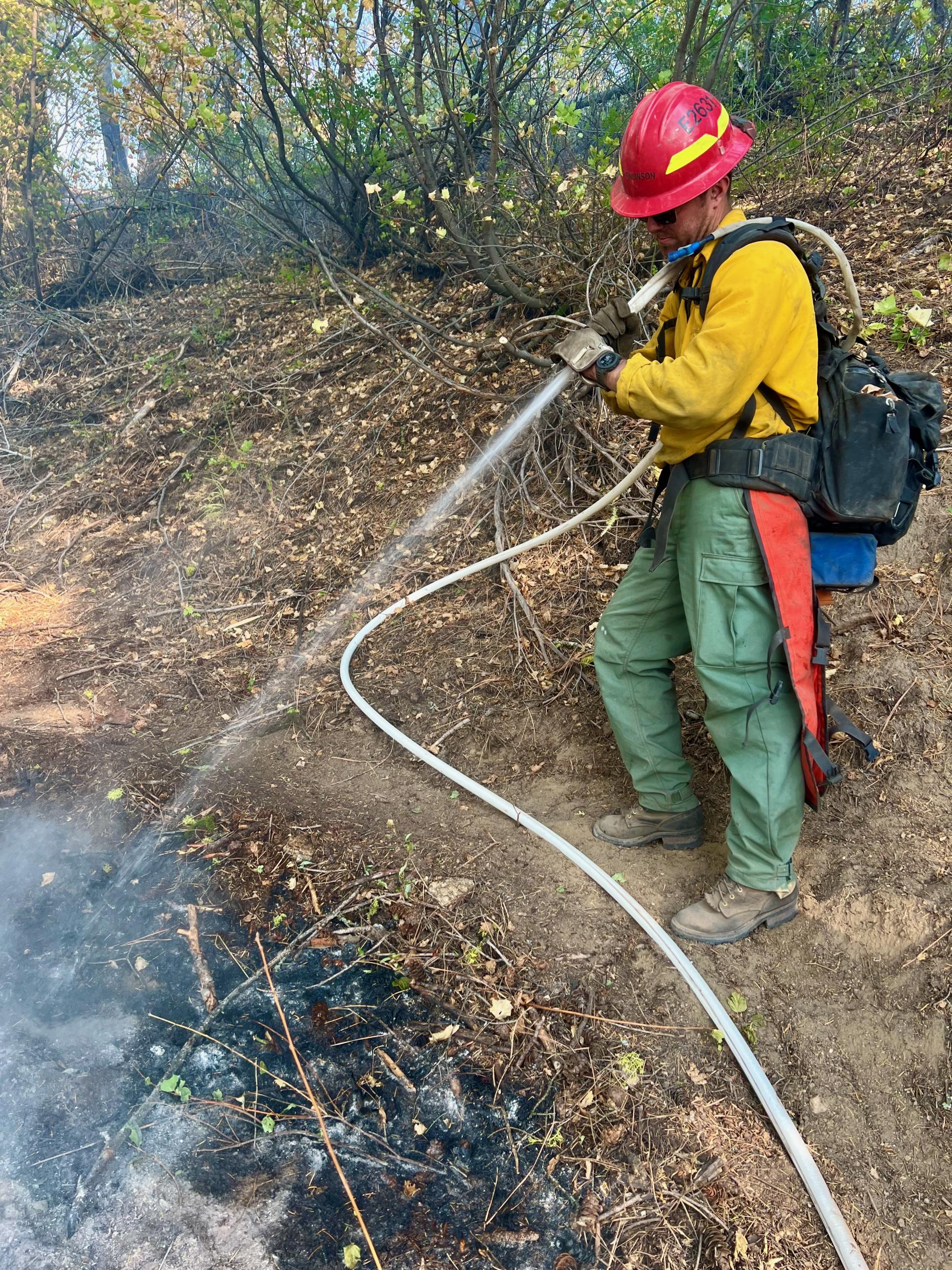 A firefighter sprays water on the hot edge of the Goat Fire on October 3, 2024.