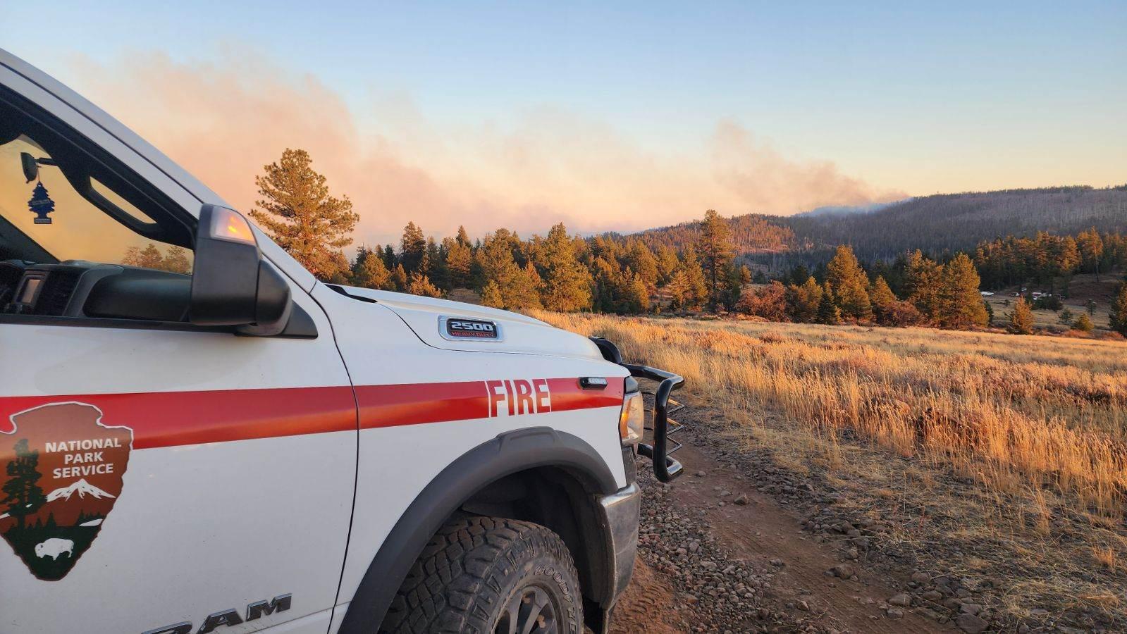 A truck in the foreground with smoke in the background