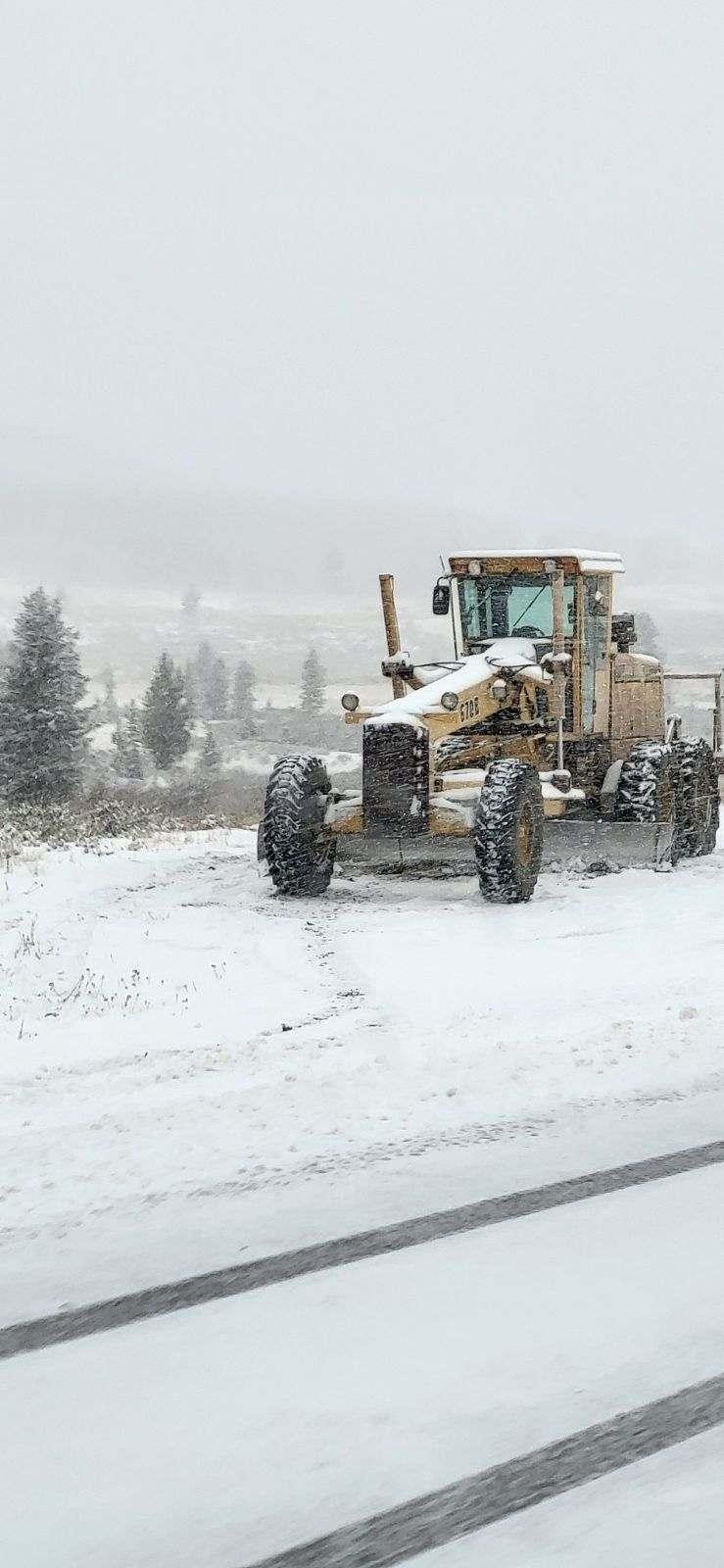 A Road Grader sits in accumulating snow on the Elk Fire, October 29, 2024