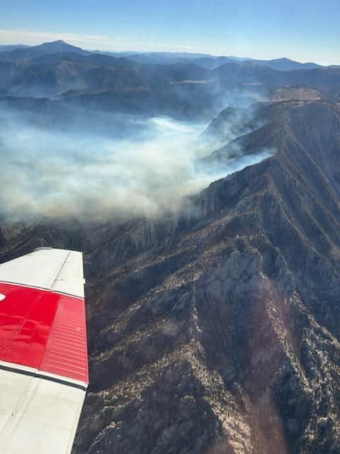 plane wing, mountains, wildfire smoke