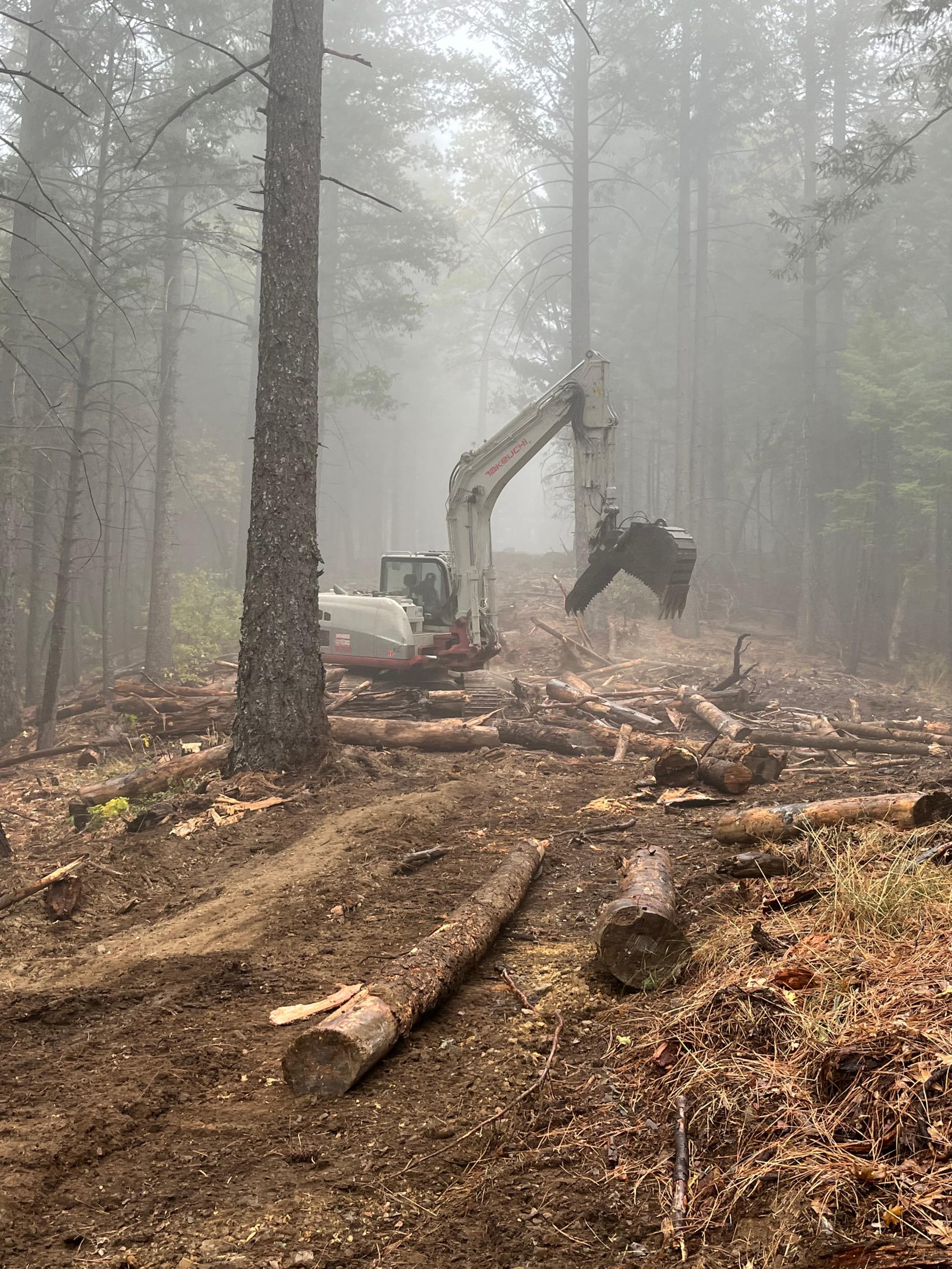 An excavator performs fire suppression repair on the west side of the fire on contingency line.