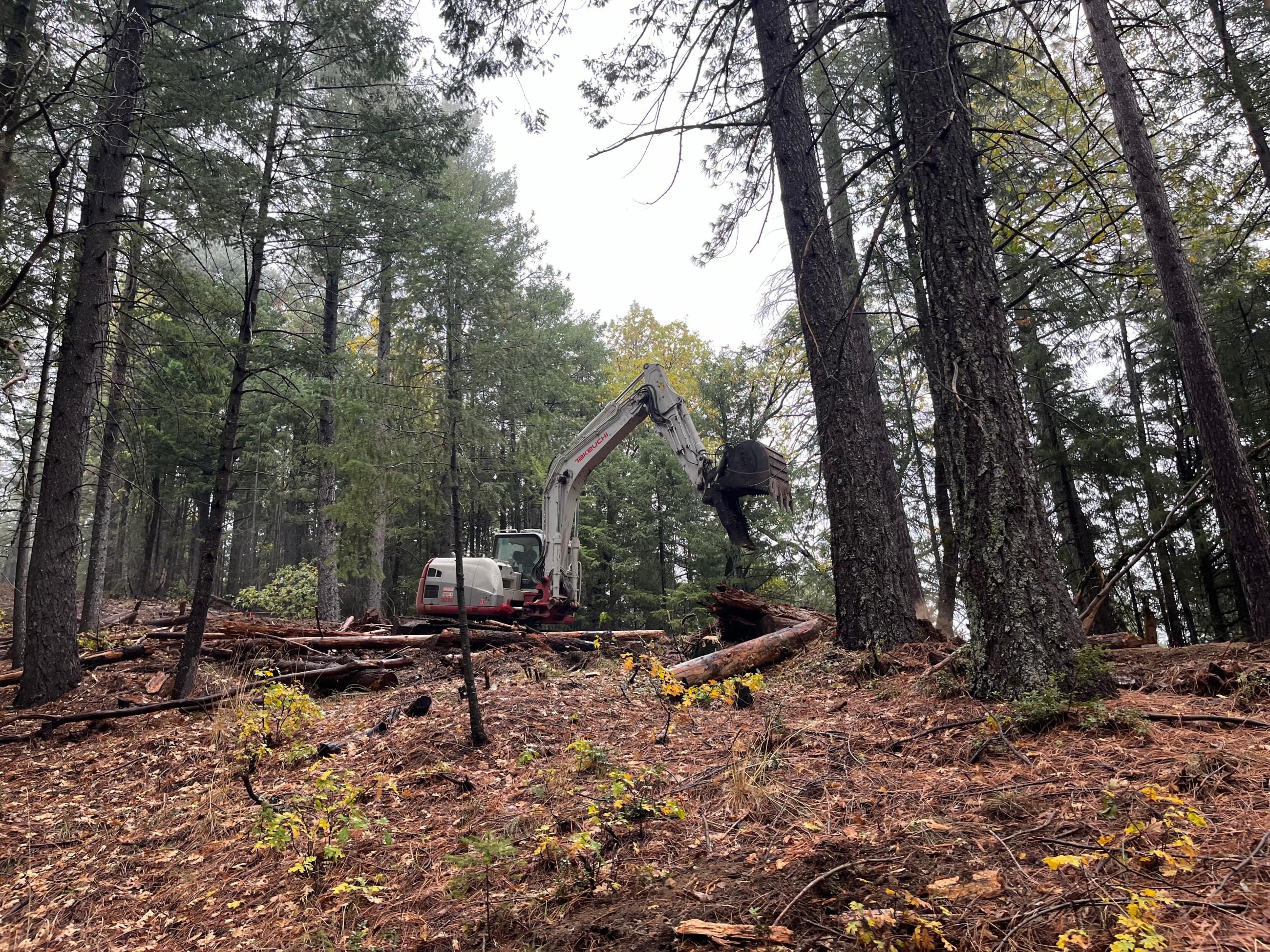 An excavator performs fire suppression repair on the west side of the fire on contingency line.