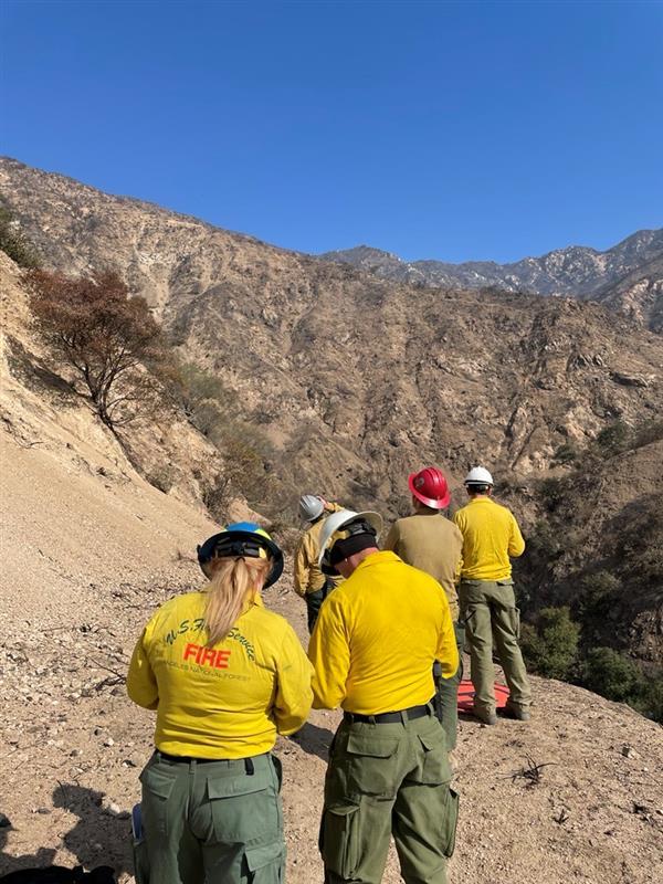 Color Photo Image showing BAER Archaeologist Joanna Huckabee and other BAER specialists assess Rubio Canyon within the Eaton burned area using drone technology