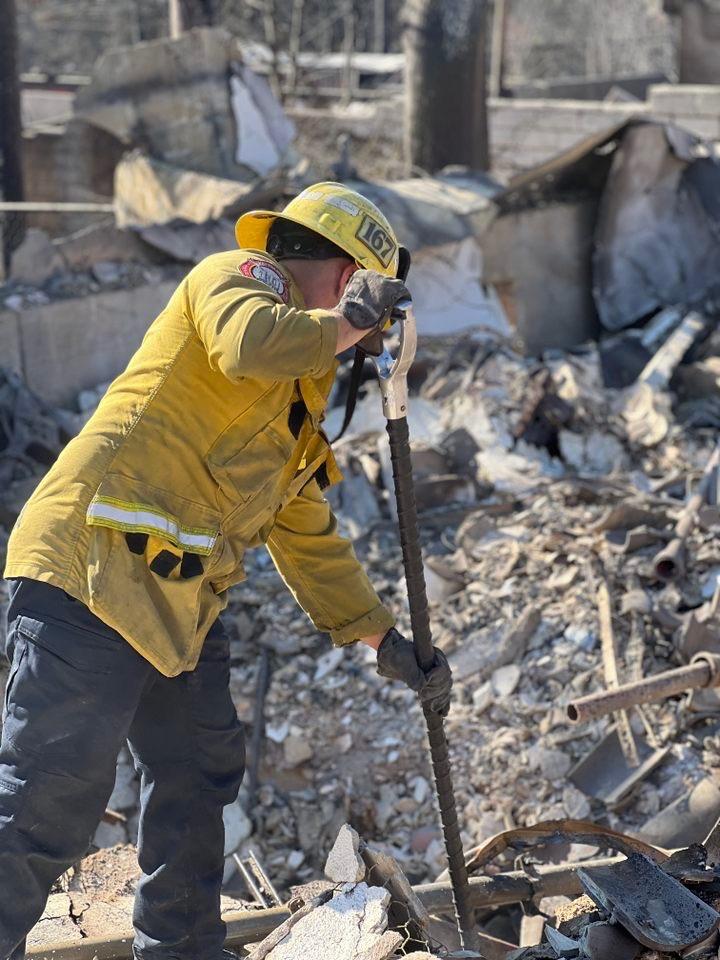 A firefighter from the Los Angeles County Fire Department’s Engine 167 working in Altadena. Using hand tools to break through debris and locate smoldering fires.