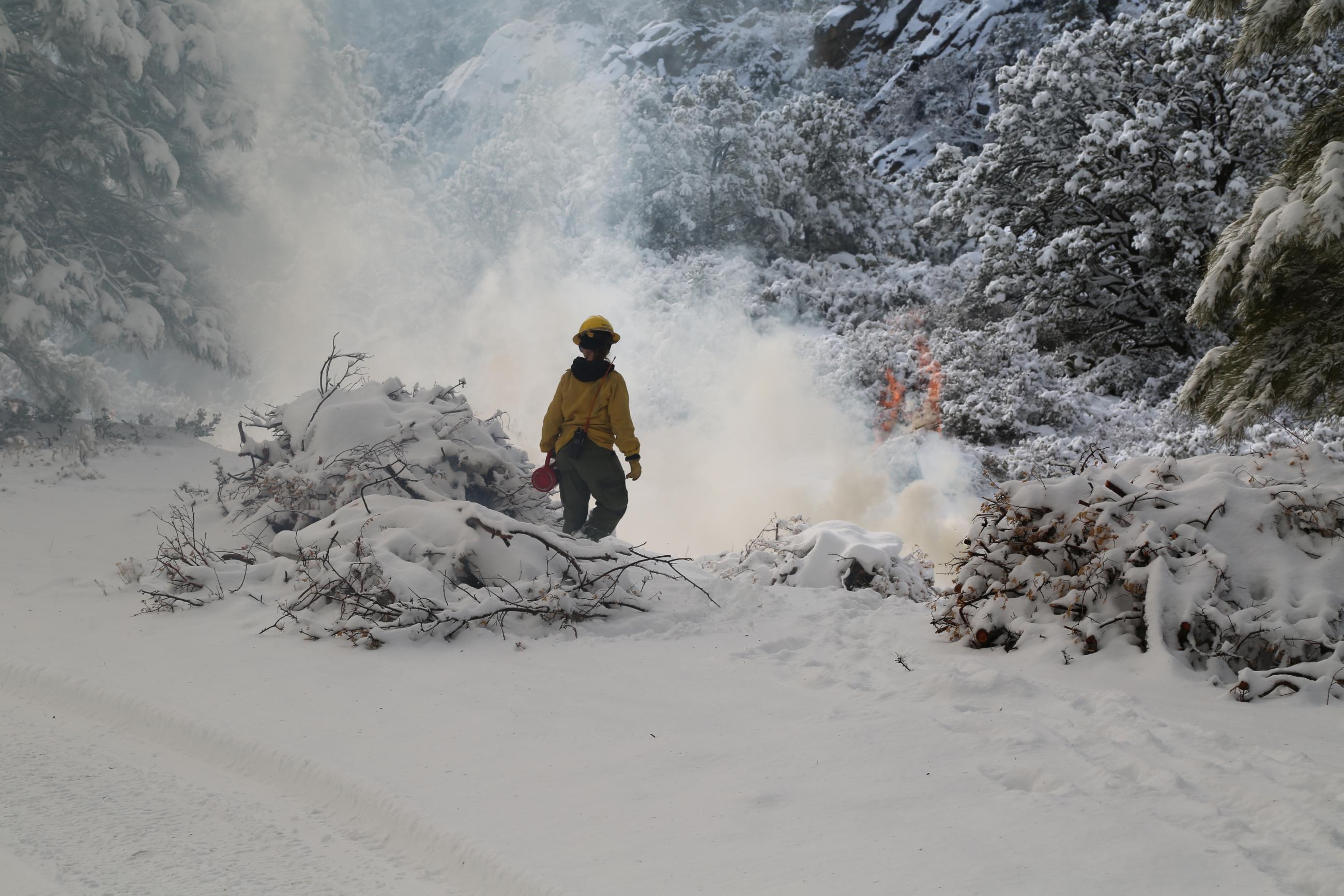 Firefighter tends burn piles.