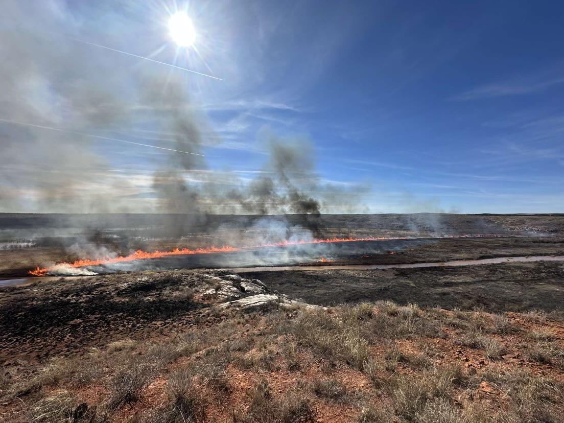 Picture of fire from the top of a hill making a run through open field on edge of Lake Meredith. 