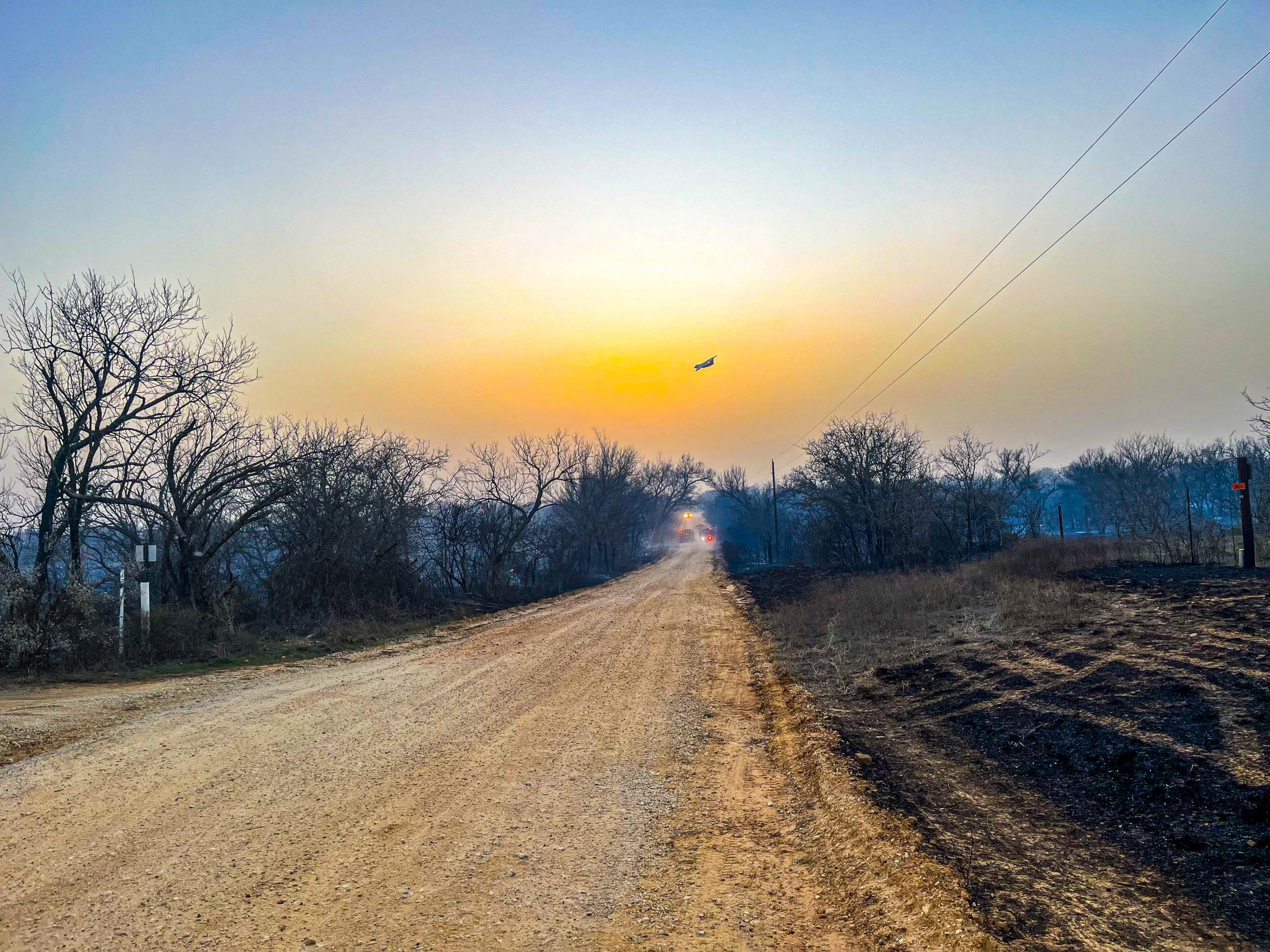 Gravel road, burnt grass, airplane in sunset