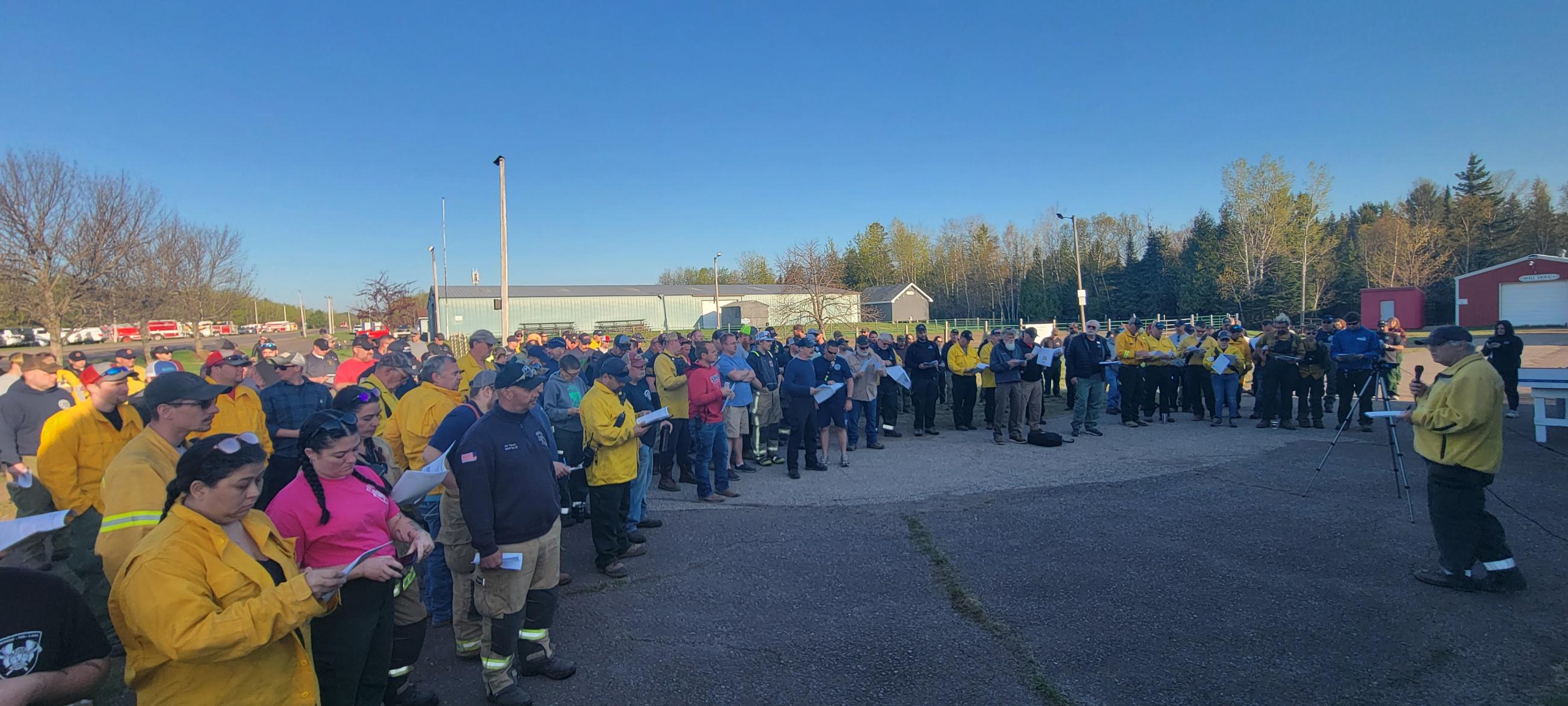 Landscape photo of firefighters standing at the morning operation briefing at the Incident Command Post