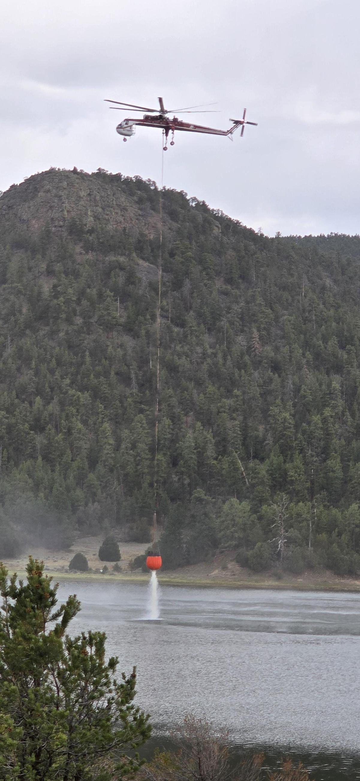 View of a helicopter lifting a bucket from a lake