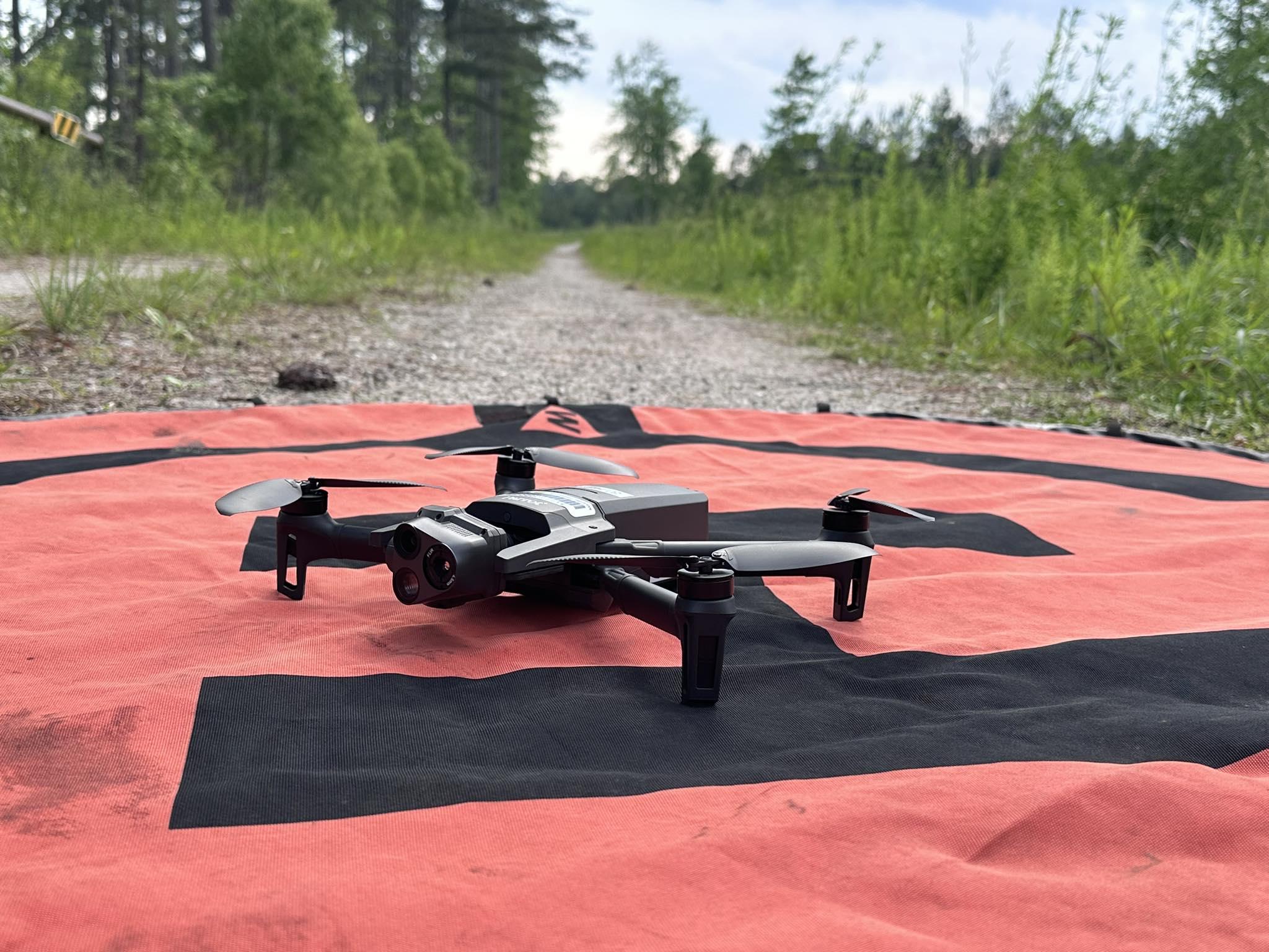 Parrot Anafi drone sits on landing mat on a dirt road
