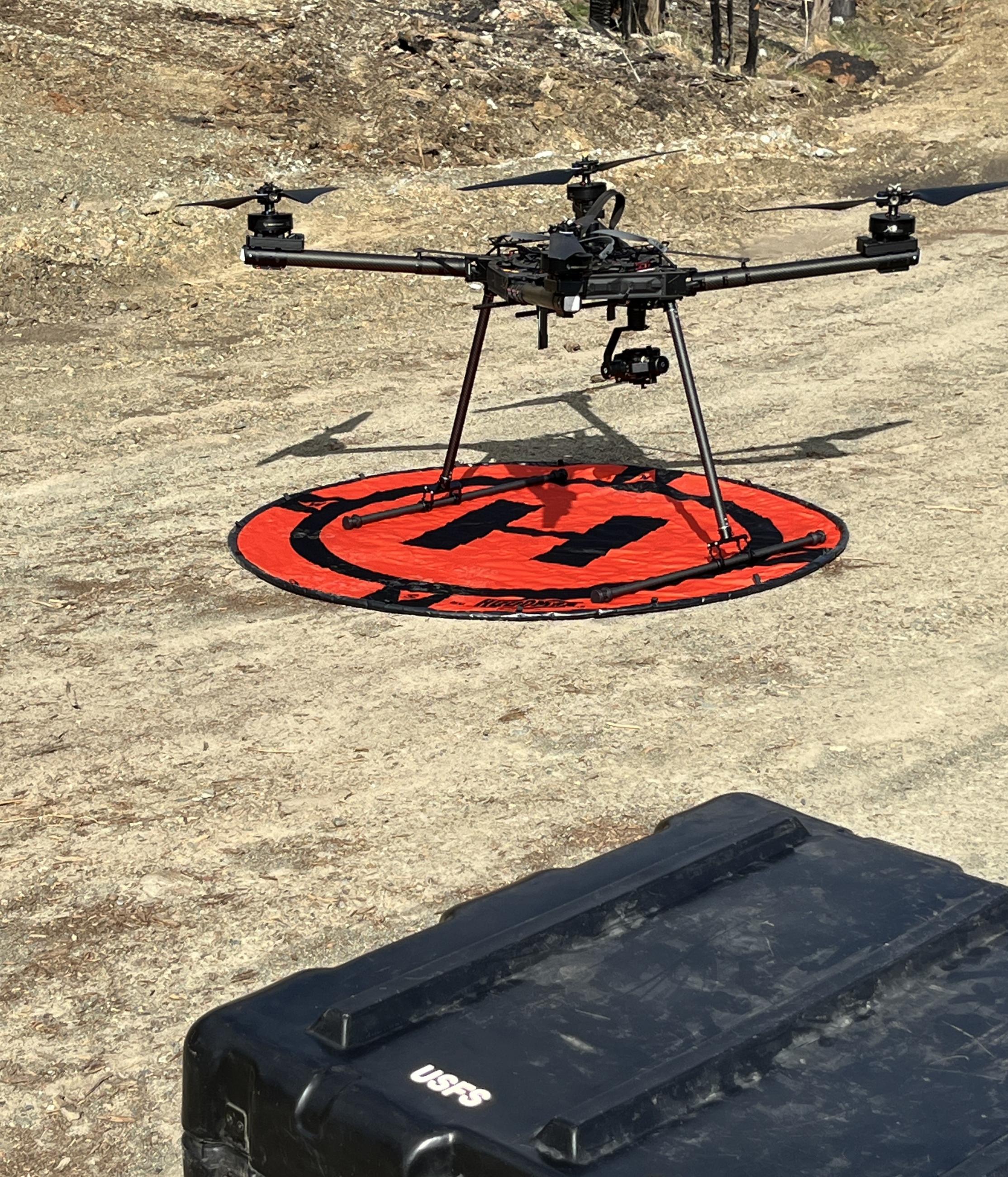 Photo of a drone on a landing pad on a dirt road