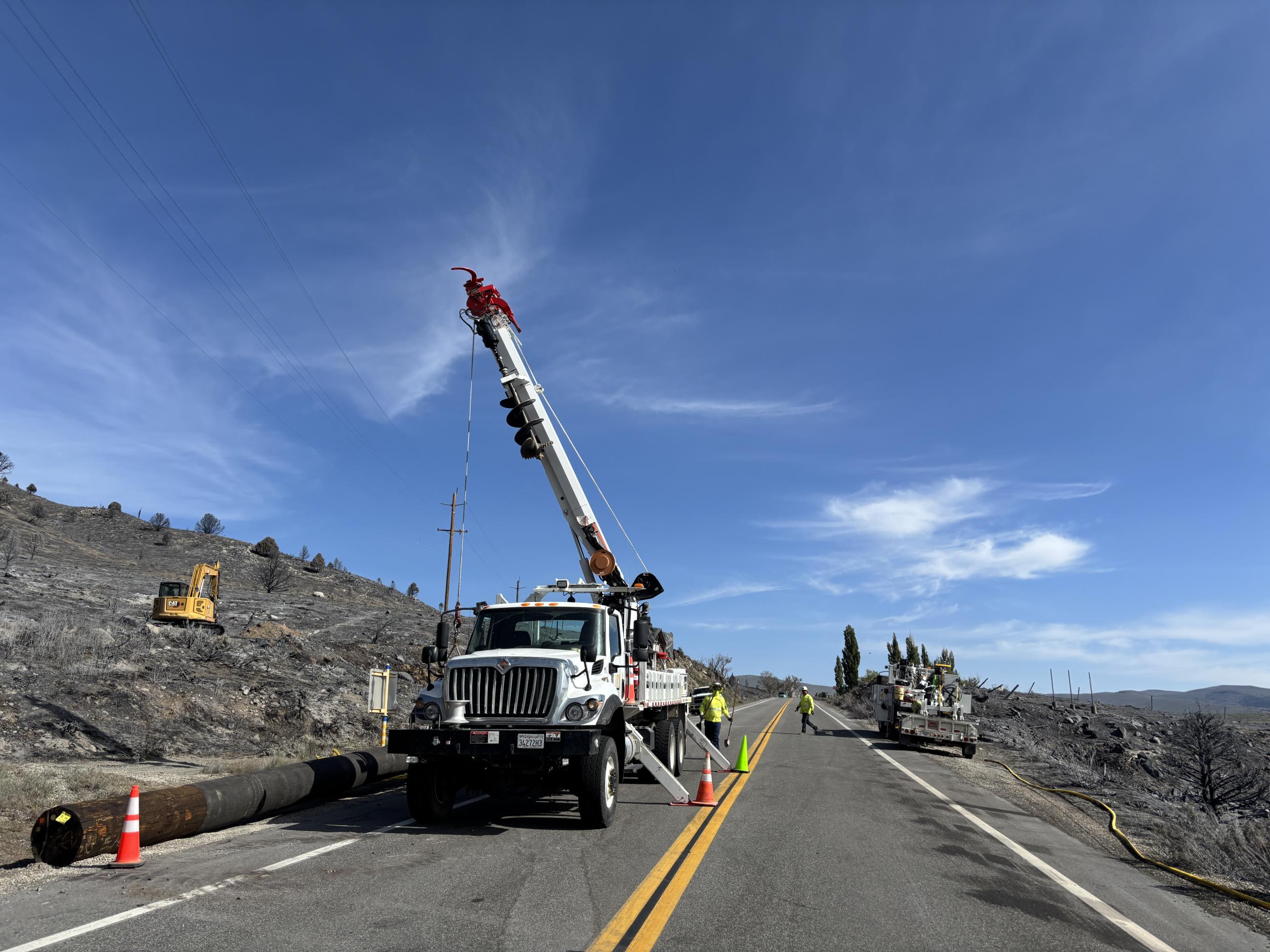 power lines, vehicles, burned hillside, sky, highway