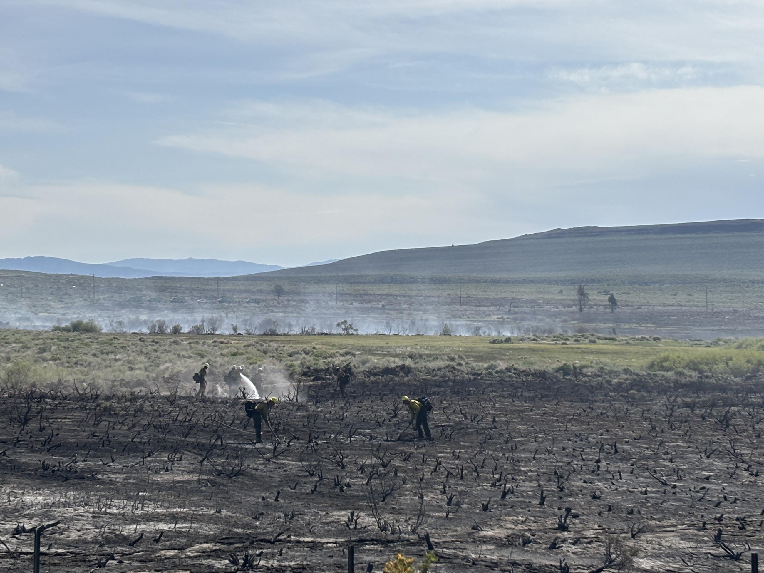 charred ground, firefighters, lake, sky, mountains
