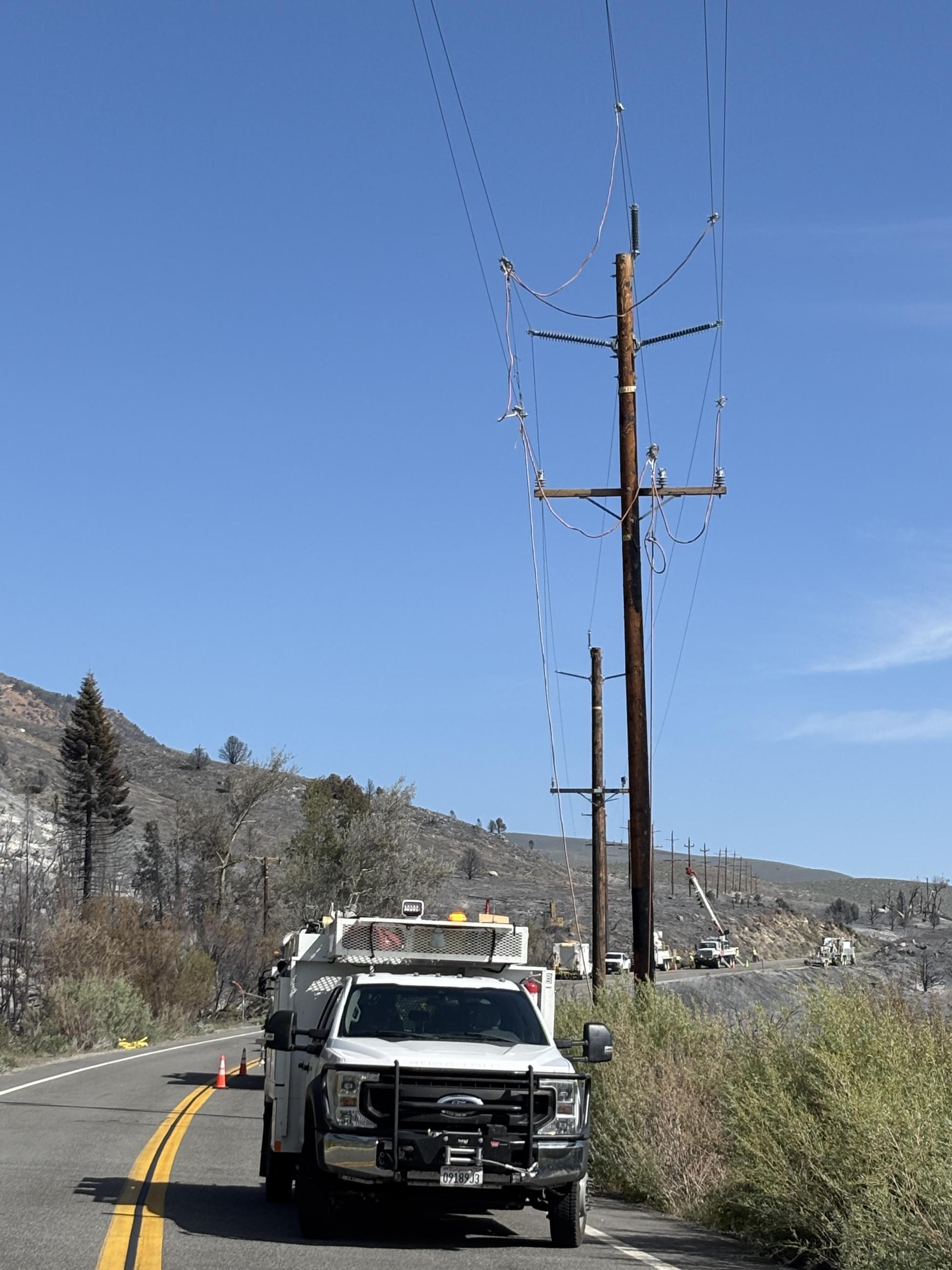 trucks, power lines, mountains, charred ground, sky