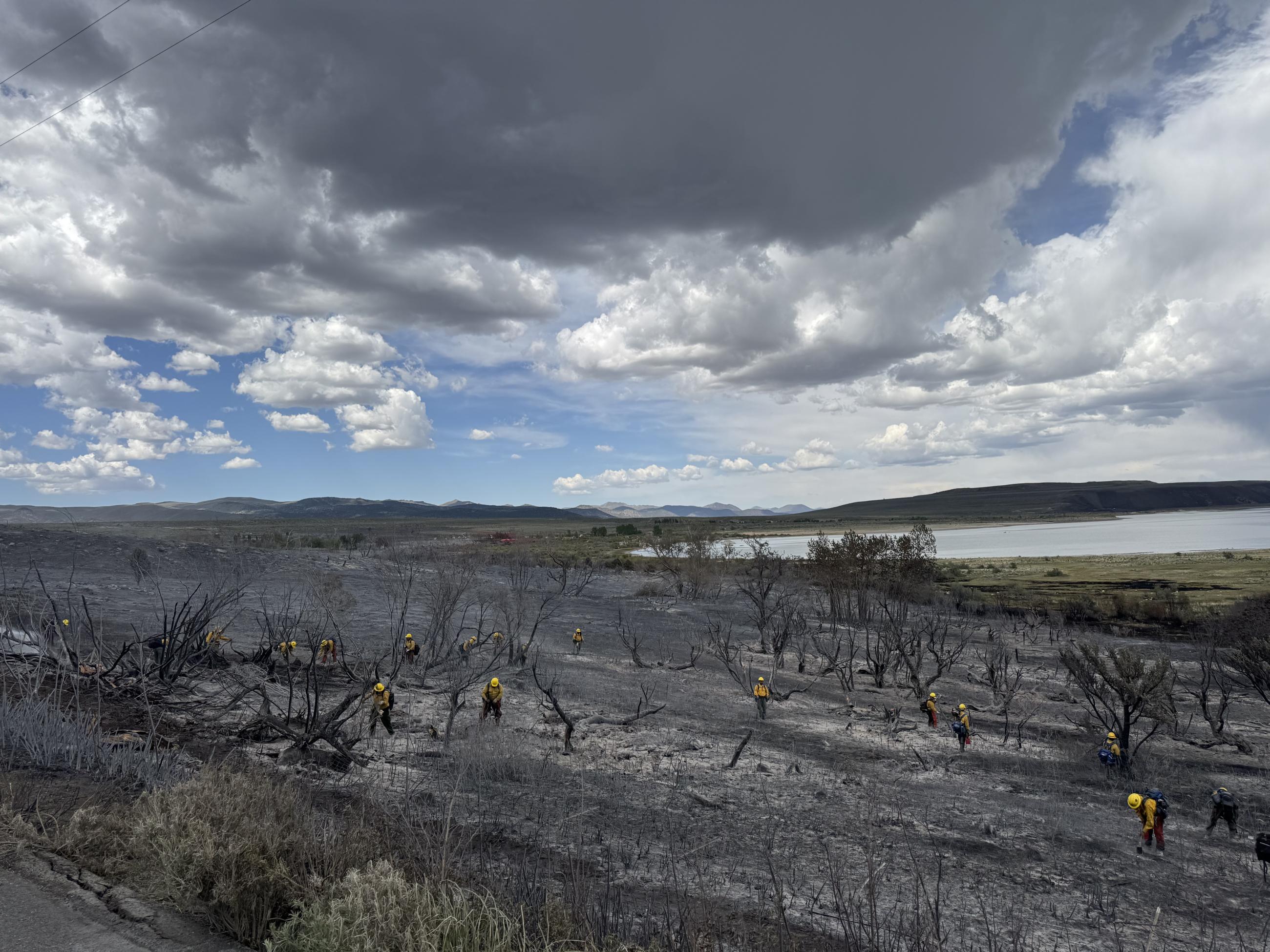 charred earth, firefighters, lake, sky