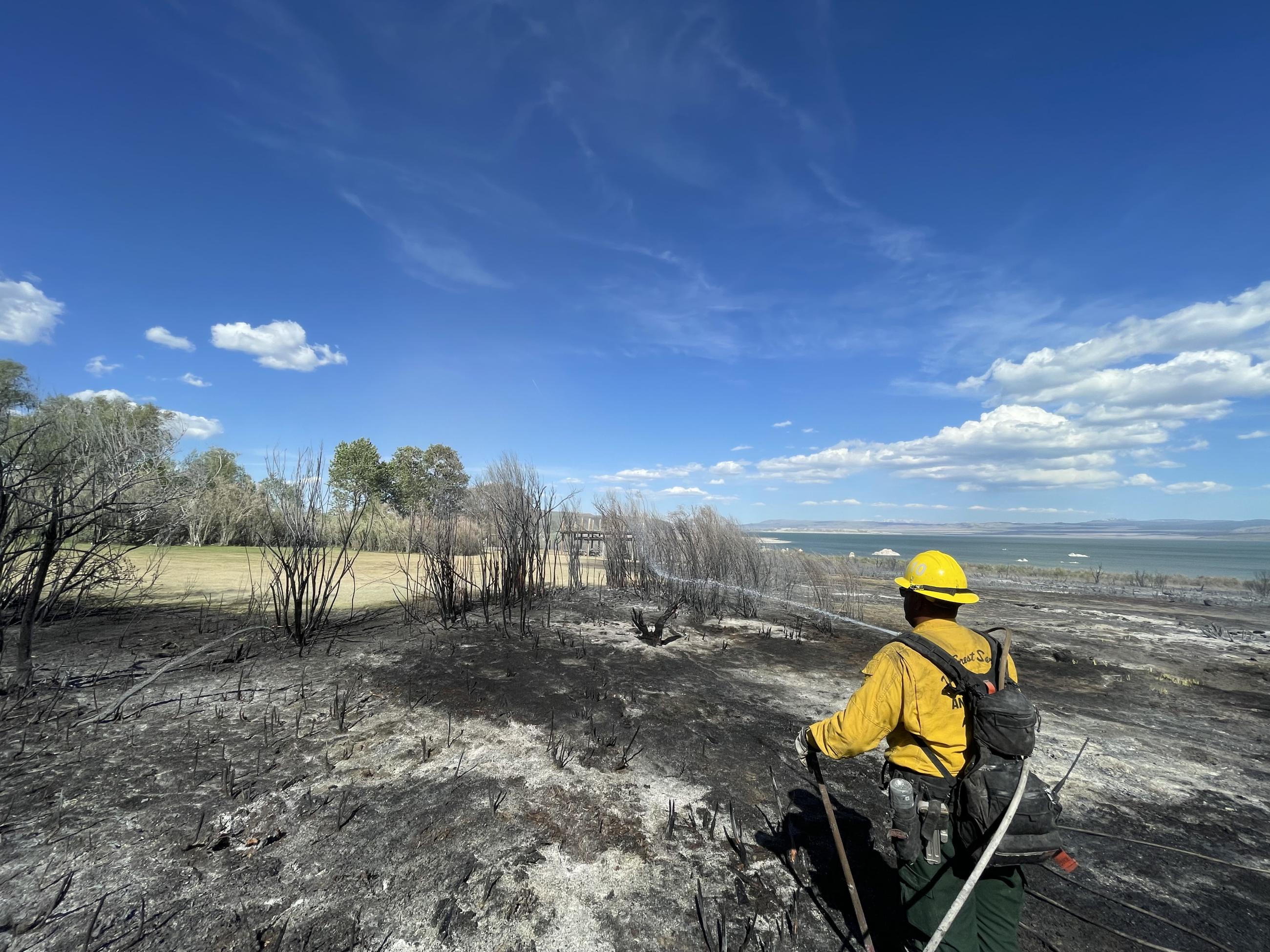 firefighter, charred ground, lake, sky